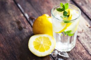 Lemonade with fresh lemon on wooden background