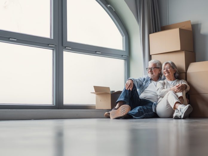 Elderly,Couple,Sits,On,The,Floor,Of,Their,New,Apartment,
