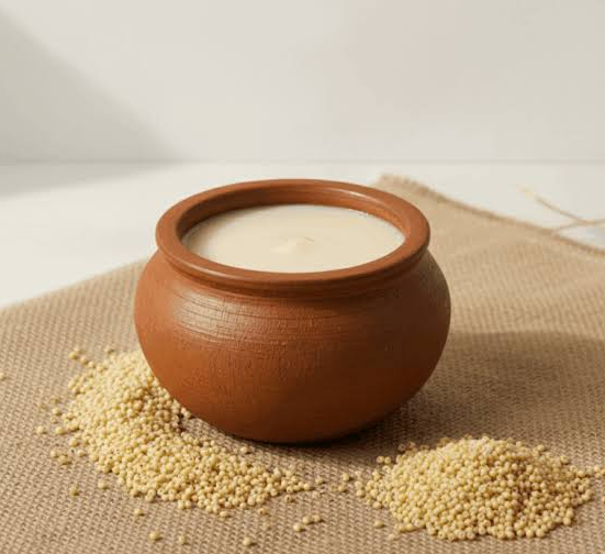 Screenshot 2026-08-04 120750 Clay pot filled with white yogurt sits on a burlap cloth, with scattered millet grains around it.