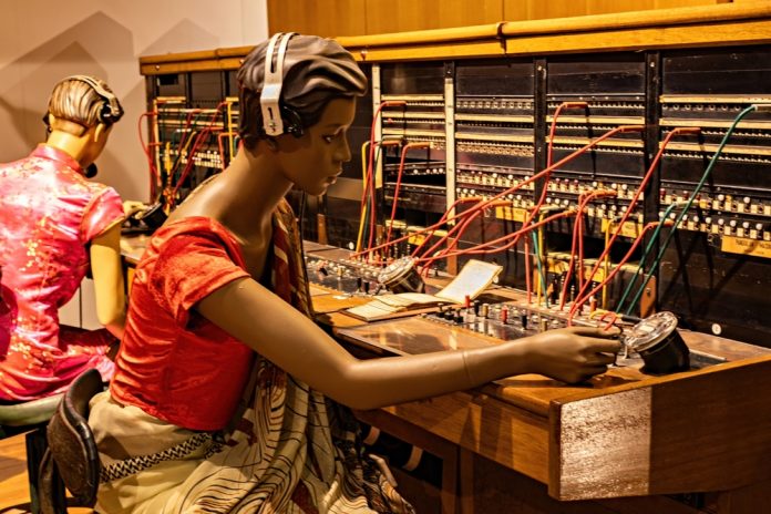Kuala,Lumpur,,Malaysia,-,October,5,,2025:,Exposition,Of,The Two mannequins with headphones operate a vintage analog control panel filled with colorful wiring and gauges, in a museum-like setting.